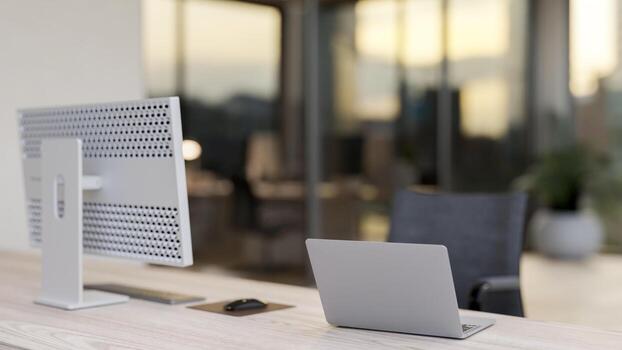 A back view of an office desk in an office building features a computer and a laptop on the desk. photo