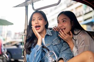 Two excited Asian girls enjoy a ride in a tuk-tuk in Thailand, amazed by the stunning views. photo