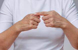 Woman index finger pointing at the first digital knuckle on hand to identifying Arthritis photo