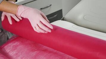 A person in a lab coat is rolling up a pink roll video