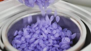 A bowl filled with purple beads being poured into a machine video