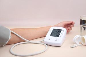 Digital blood pressure tonometer and pack of pills on a light background with copy space. photo