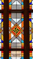 A close-up of an intricate stained glass window inside Konigsberg Cathedral in Kaliningrad. The geometric pattern features vibrant colors, including red, yellow, and blue, with a green clover design photo