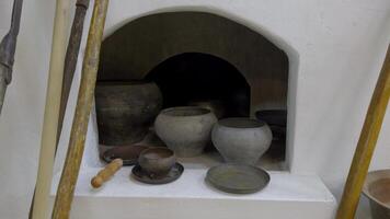 A close-up view of various old clay pots and bowls in a traditional Russian brick oven. The soft lighting highlights the textures of the handcrafted pottery, creating a rustic atmosphere. Photographed video