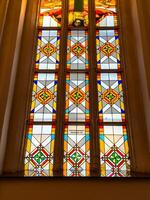Stunning stained glass windows with geometric patterns and religious symbols inside Konigsberg Cathedral in Kaliningrad. The warm sunlight highlights the rich colors red, yellow, blue, and green photo