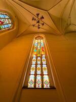 Stunning stained glass windows with geometric patterns and religious symbols inside Konigsberg Cathedral in Kaliningrad. The warm sunlight highlights the rich colors red, yellow, blue, and green photo