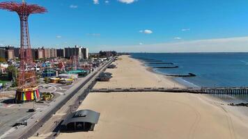Aerial view Iconic Pier with Coney Island Skyline and Amusement Park, A stunning view of a wooden pier extending over the ocean, video