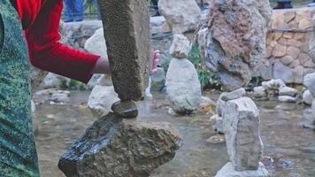 An unidentified man in Kislovodsk installs balancing stones. Stones lie on top of each other in balance in a babbling river. concept of calm and patience video
