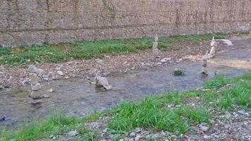 Medium shot of stones lying on top of each other in balance in a babbling river. concept of calm and patience, feng shui near the pond. pyramid of stones stacked video
