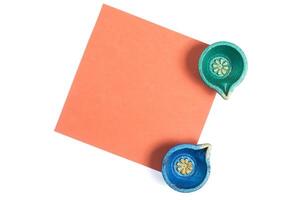 Diwali greeting card with colorful clay lamps and blank orange paper note for text photo