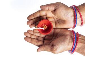 Top view of Indian woman's hands holding Diwali Diya on white background photo