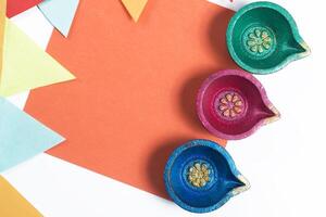 Three colorful decorative Diyas on vibrant orange paper with decorative flag for Diwali celebration photo