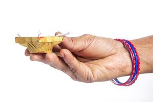 Close-up of hand holding traditional Indian oil lamp with colorful bangles photo