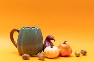 Still life with pumpkins, apples, acorns and jug on orange background photo