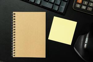 Top view of notebook. Blank paper notepad on office desk table with keyboard and other supplies. Blank notebook page for input the text. copy space, flat lay. photo