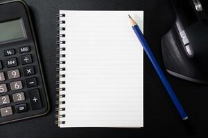 Top view of notebook. Blank paper notepad on office desk table with keyboard and other supplies. Blank notebook page for input the text. copy space, flat lay. photo