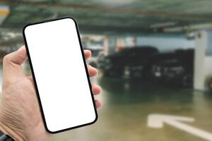 Mockup blank screen mobile phone for app or web site mockup. Smart phone with white screen in hand on Blur car parking background. photo