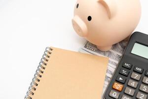 Piggy bank, Notebook with calculator isolated on white background, financial goal, money saving concept with copy space. Budget planning concept. photo