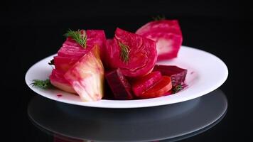 pickled cabbage with beets and carrots, in a plate, isolated on black background video