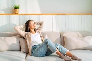 Carefree Asian woman relaxing and sitting on a sofa at home in the morning photo