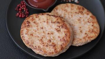 Grilled chicken burger cutlet with salt, spices and herbs on a dark concrete background video