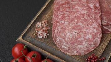 Antipasto jamon, prosciutto, sausage, sliced with tomatoes, salt and spices on a dark concrete background video