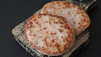 Grilled chicken burger cutlet with salt, spices and herbs on a dark concrete background video