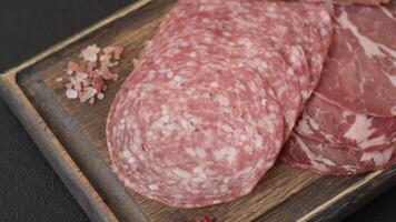 Antipasto jamon, prosciutto, sausage, sliced with tomatoes, salt and spices on a dark concrete background video