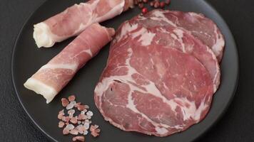 Antipasto jamon, prosciutto, sausage, sliced with tomatoes, salt and spices on a dark concrete background video