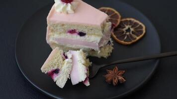 Piece of sweet cake with pink cream with raspberry flavor, with shortbread, cheesecake on a dark concrete background video