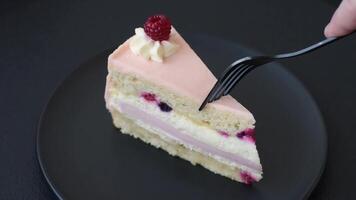 Piece of sweet cake with pink cream with raspberry flavor, with shortbread, cheesecake on a dark concrete background video