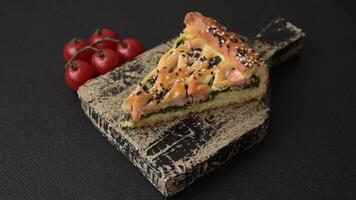 Pieces of quiche with salmon, spinach or broccoli, salt and spices on a dark concrete background video