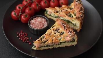 Pieces of quiche with salmon, spinach or broccoli, salt and spices on a dark concrete background video