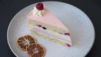Piece of sweet cake with pink cream with raspberry flavor, with shortbread, cheesecake on a dark concrete background video