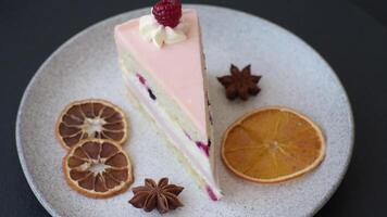 Piece of sweet cake with pink cream with raspberry flavor, with shortbread, cheesecake on a dark concrete background video