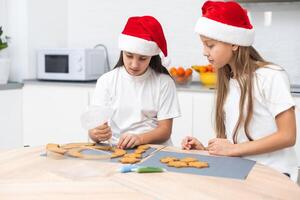 Two girls sisters are playing around in the kitchen after making Christmas cookies, they draw with flour on the table and on their faces. Christmas, New Year concept photo