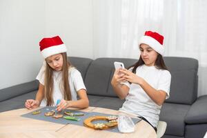 Two girls sisters are playing around in the kitchen after making Christmas cookies, they draw with flour on the table and on their faces. Christmas, New Year concept photo