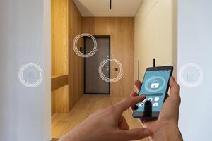 smart house, home automation, device with app icons. woman uses his smartphone with smarthome security app to unlock the door of his house. photo