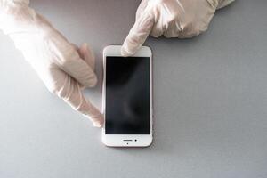 Blank smartphone held in hand in blue protective glove, isolated on white background. Copy space for a text. photo