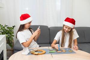 Two girls sisters are playing around in the kitchen after making Christmas cookies, they draw with flour on the table and on their faces. Christmas, New Year concept photo