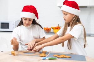 Two girls sisters are playing around in the kitchen after making Christmas cookies, they draw with flour on the table and on their faces. Christmas, New Year concept photo