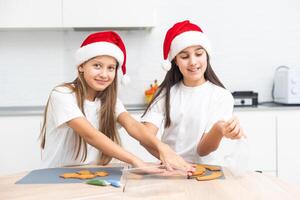 Two girls sisters are playing around in the kitchen after making Christmas cookies, they draw with flour on the table and on their faces. Christmas, New Year concept photo