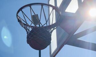 Basketball scoring a basket as it goes through the hoop and making a swish in the net photo