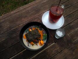 A top-down view of a ramen and traditional drinks served on a rustic wooden table. photo