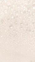 A close-up view of numerous water droplets on a transparent surface, creating a soft, dreamy texture with a white and pastel background. photo