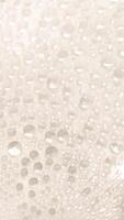 A close-up view of numerous water droplets on a transparent surface, creating a soft, dreamy texture with a white and pastel background. photo