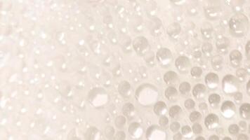 A close-up view of numerous water droplets on a transparent surface, creating a soft, dreamy texture with a white and pastel background. photo