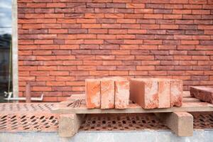 a new House is being built, the beginning of brickwork with red bricks, building materials, a pattern of stones, a natural background. High quality photo