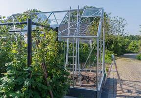 Gardener installs glass on roof of greenhouse in his garden, DIY concept and grow vegetables in small garden plot, photo