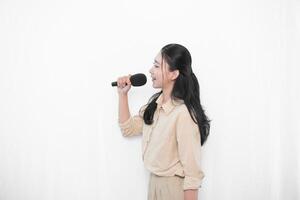 Expression of an Indonesian Asian model woman in white singing using a microphone photo